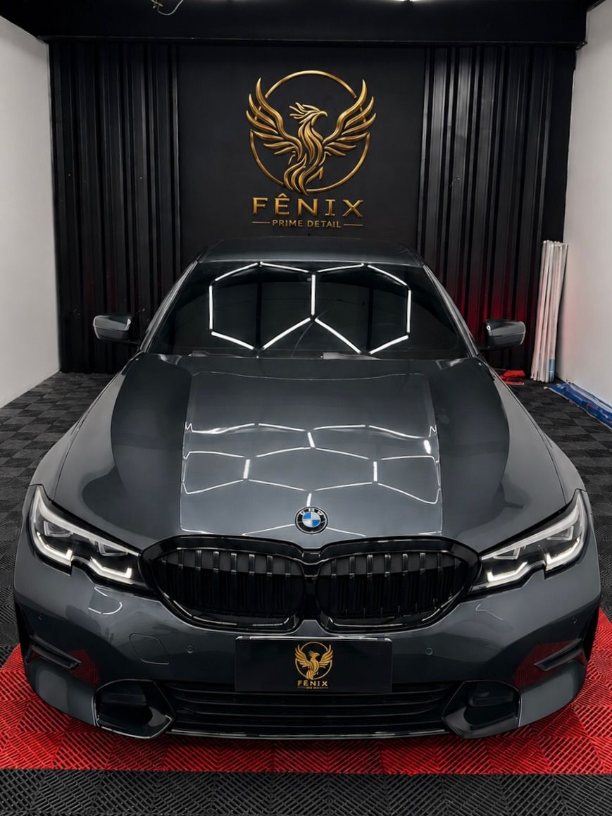 BMW Série 3 cinza de frente com pintura polida refletindo a iluminação do estúdio